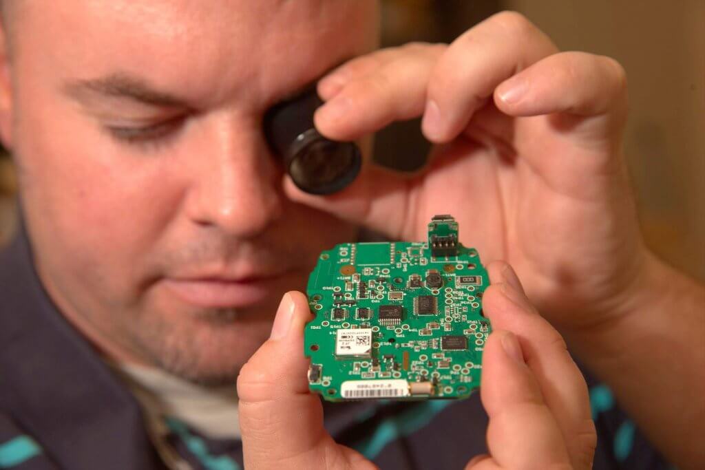 A Globalstar worker uses a small magnifying glass to study a computer chip