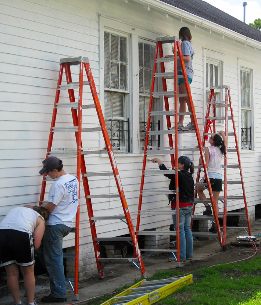 Volunteers work together to paint a house
