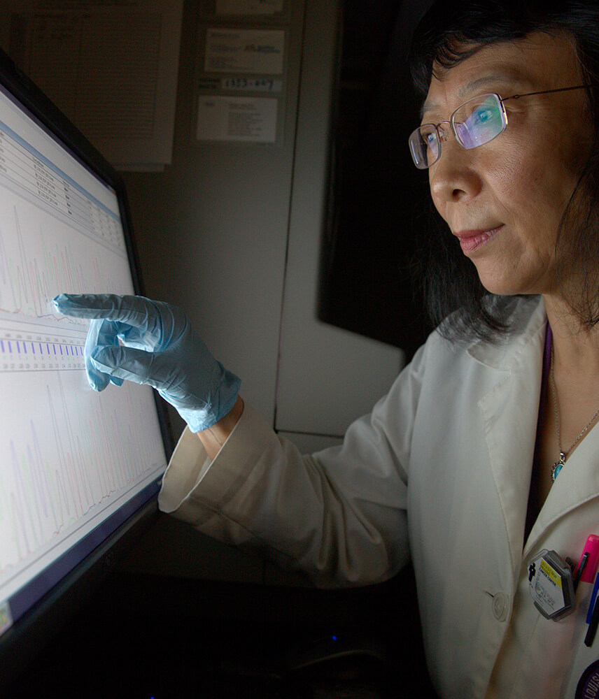 A cancer researcher intensely studies the results of tests on her screen