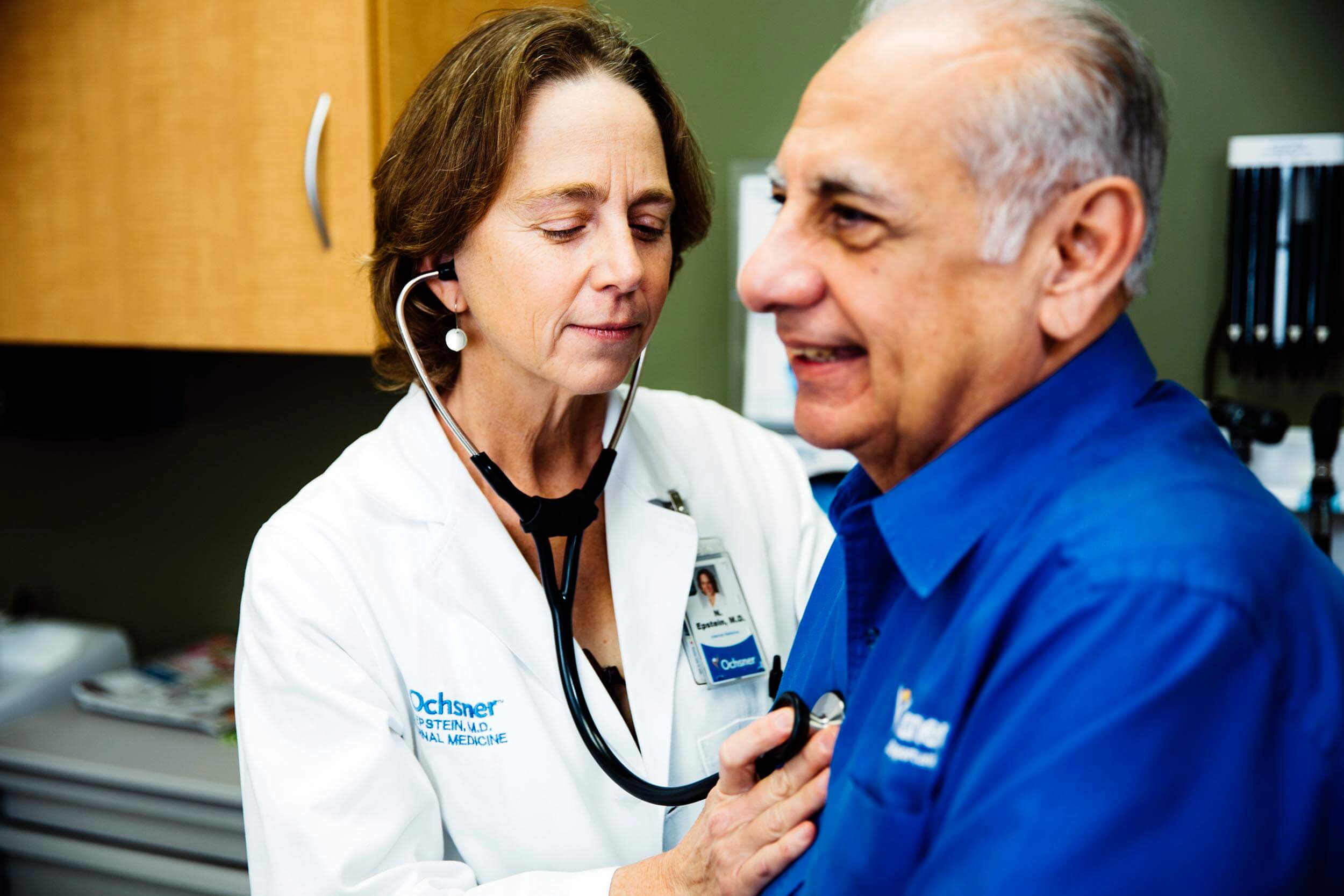 Female doctor checking pulse of older male patient using a stethoscope at Ochsner