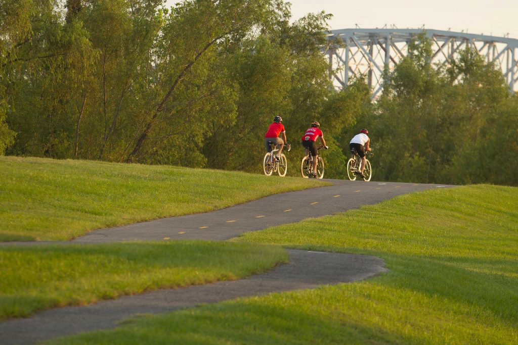 Three people ride a bike trail in New Orleans, LA