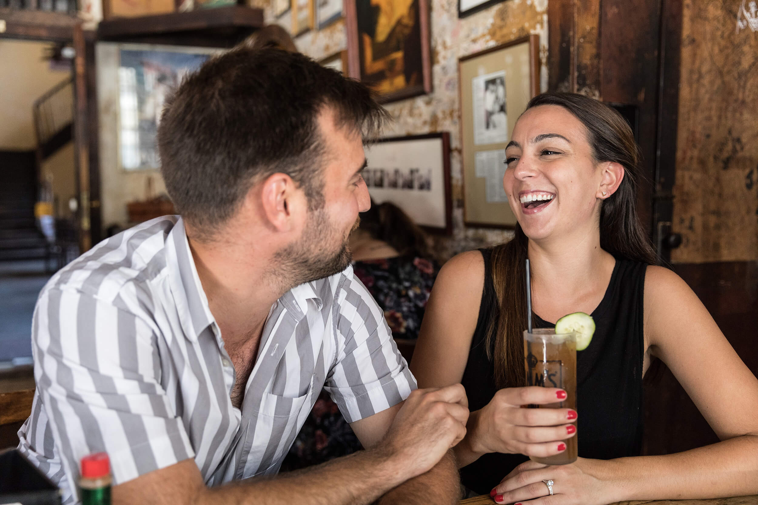 A young couple sits at a local bar laughing in New Orleans, LA