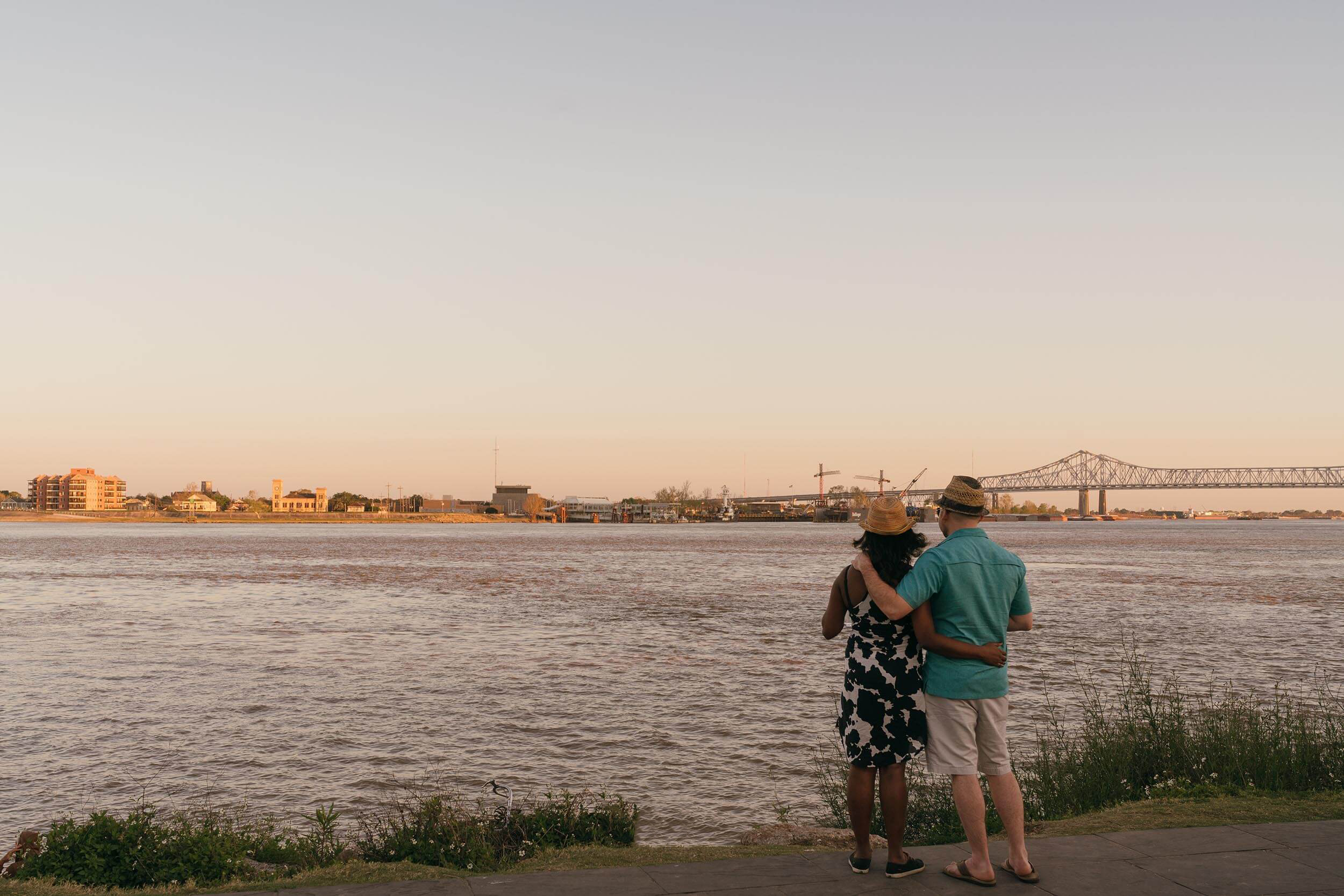 A couple stands side by side looking out over a river in New Orleans, LA